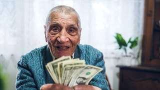 senior man counting cash money bills social security retire invest inflation cola getty.jpg