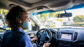 Woman wearing face mask driving her car and s.width HlXYHag.jpg