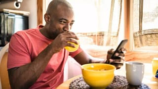 man holding phone eating breakfast EnRgBMr.width .jpg