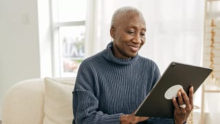 older person sitting on a couch looking at a tablet.jpg