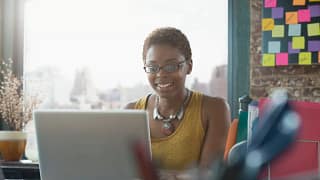 Woman smiling as she uses her laptop yKHtHfd.width .jpg