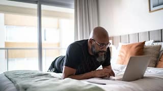 person lying on bed using laptop zxzVvg.width .jpg