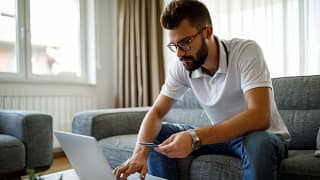person on couch with laptop and credit card .width .jpg