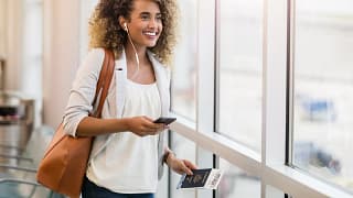 woman smiling in airport with suitcase and pa.width zsxbQ.jpg