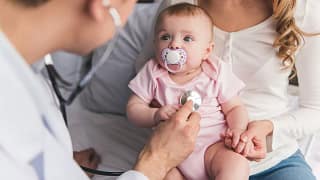 Baby in mothers lap staring up at doctor Byju.width .jpg