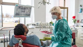 Man in chair at dentist office communicating .width .jpg