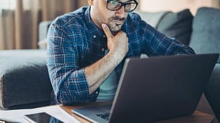 Man with glasses looking at laptop kjgn.width .jpg