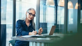 Woman reading paperwork at a desk FZuNqt.width .jpg