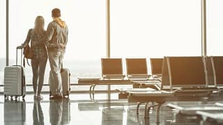 couple with suitcases at airport window.width .jpg