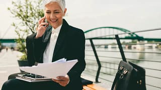 mature senior businesswoman woman on phone looking at documents.jpg