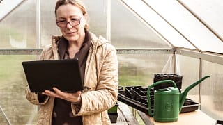 mature woman with glasses and laptop in greenhouse.jpg