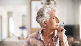 older person looking thoughtful while holding a pen.jpg