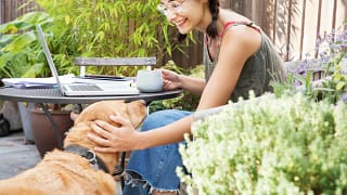 woman petting dog with laptop outside CAJazq.width .jpg