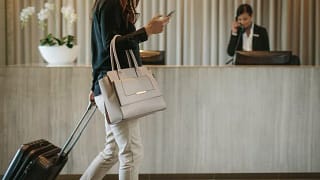 woman with suitcase and phone in hotel lobby.width .jpg