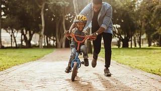 Dad helping young son ride bike RZUCj.width .jpg