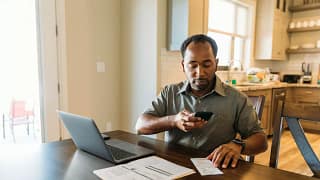 Man sits at counter with phone on laptop util.width QUam.jpg