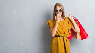 Woman holding shopping bags hand over mouth j.width .jpg