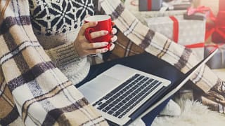 Woman on laptop with blanket and presents RZZ.width .jpg
