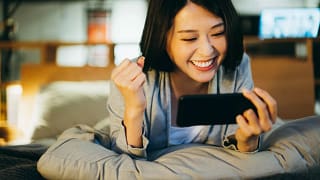 excited person lying on bed looking at phone screen.jpg