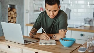 man at table writing in notebook NHASUaV.width .jpg