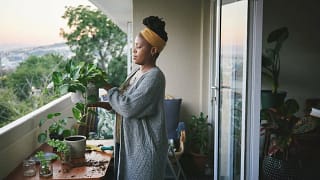 person with plants on balcony WBfBkd.width .jpg
