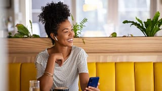 smiling person holding phone sitting in coffee shop.jpg