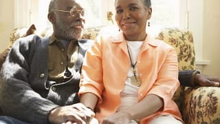 two older people sitting on a couch holding hands.jpg