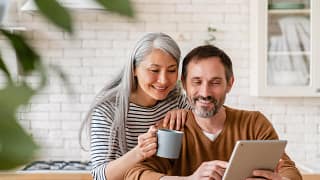 two people smiling and looking at a tablet.jpg
