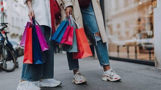 two women holding shopping bags on street.width .jpg
