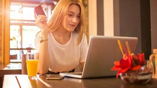 young adult woman at laptop holding credit ca.width xwXgoK.jpg