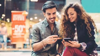 young couple at mall with phone and credit ca.width .jpg