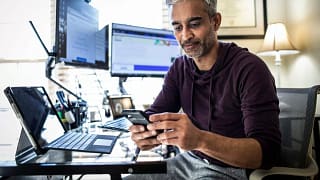 Man using is cell phone while sitting at desk.width zOrjm.jpg