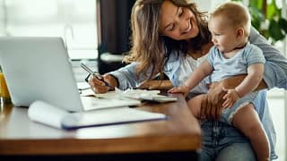 Woman working on taxes while holding infant i.width GkqVTs.jpg