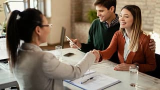 couple signing mortgage and shaking hands wit.width .jpg