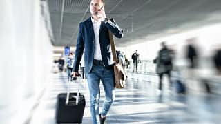 man in airport with suitcase and on the phone.width .jpg