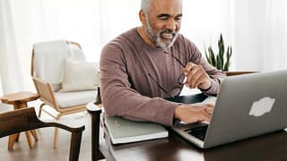 smiling person holding glasses and looking at laptop.jpg