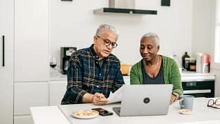 two people sitting in a kitchen looking at a laptop.jpg
