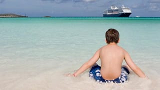 Child on shore of beach with cruise ship off .width .jpg