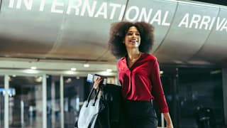 Smiling traveler walks through airport with l.width .jpg
