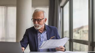 older worker holding paper and looking at laptop.jpg