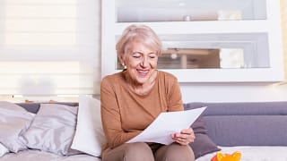 senior woman smiling reading document gettyimages .jpg