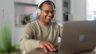 smiling person at laptop wearing headphones gettyimages .jpg