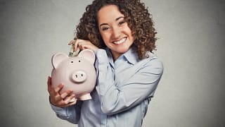 woman putting money in piggy bank smiling retirement saving.jpg