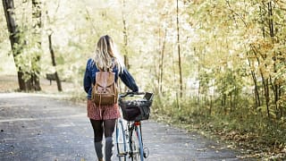 woman walking bike through park.width .jpg