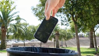 Hand dropping a smartphone into a waste baske.width .jpg