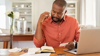 Man on phone with laptop documents qaawUT.width .jpg