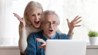 getty couple looking at laptop and exclaiming in happiness happy surprised thrilled.jpg