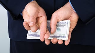 money behind back fingers crossed corporate tax getty.jpg
