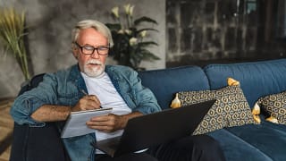 senior holding laptop and writing note in notebook.jpg