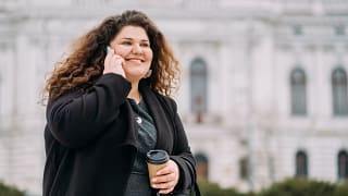 getty happy smiling person on phone in front of building.jpg